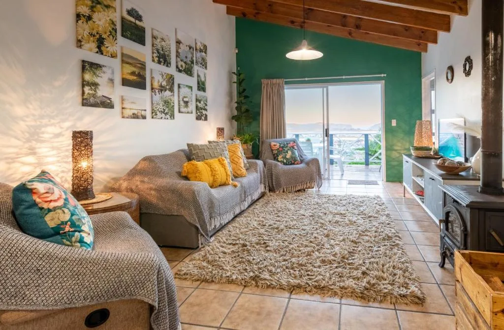 Spacious living room with comfortable seating, green accent wall, and lagoon views