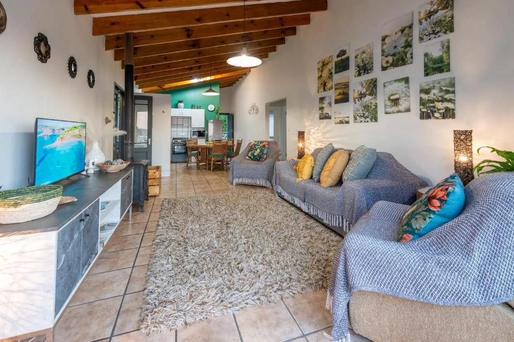 Spacious lounge with gray sofa, TV, wooden beams, and garden route photography