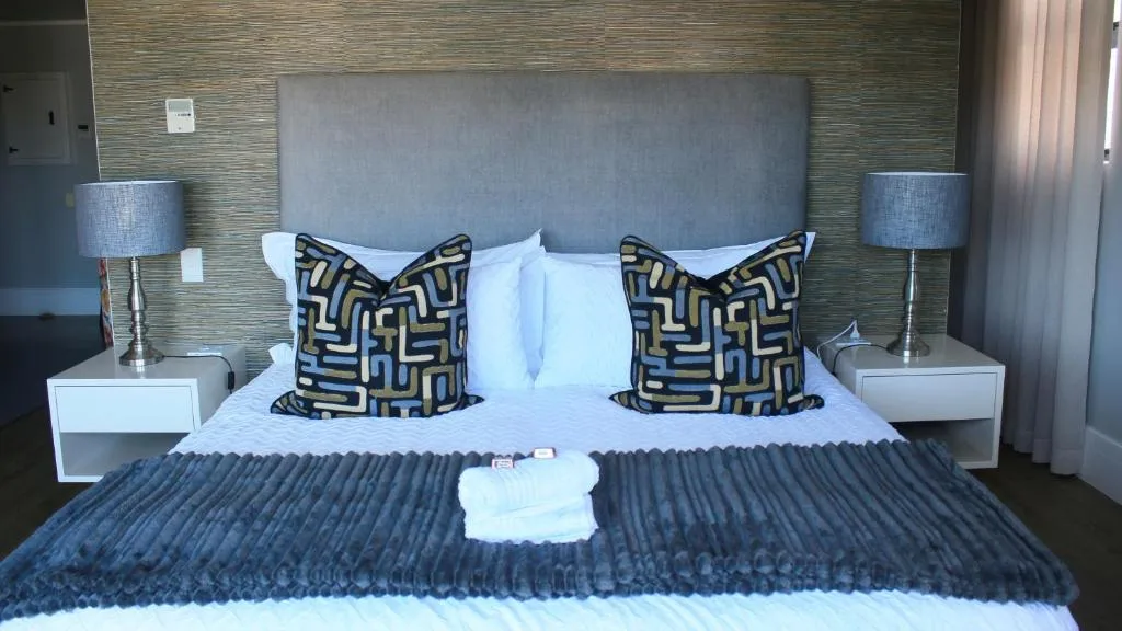Modern bedroom with gray upholstered headboard and patterned accent pillows
