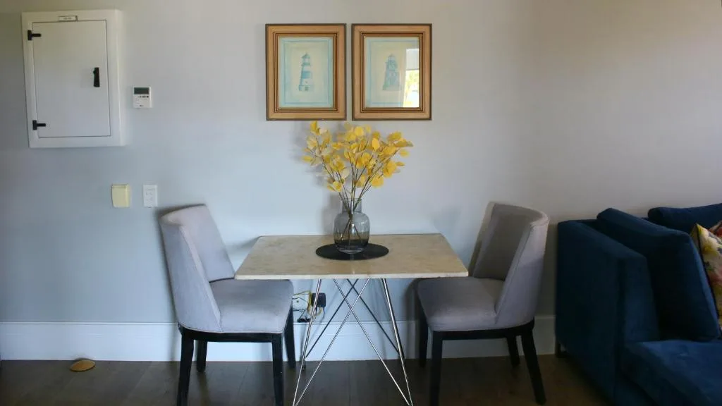 Modern dining table with two upholstered chairs and yellow flower arrangement