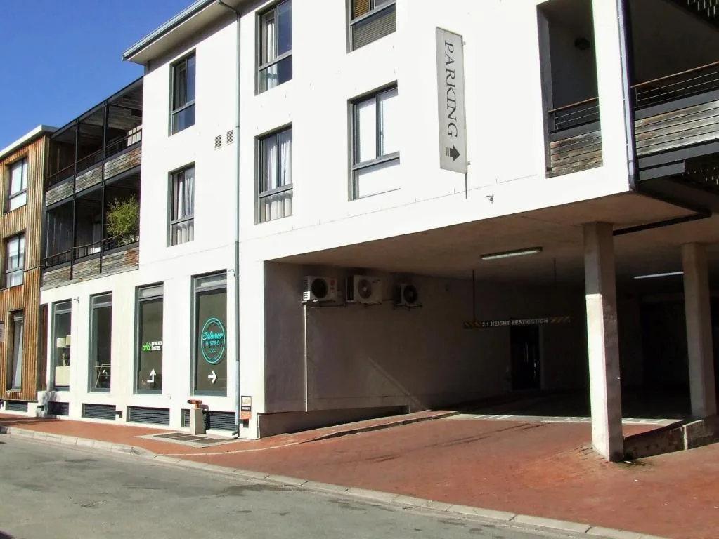 Modern white building facade with parking area and ground floor retail