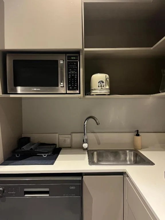 Compact kitchen with microwave, sink, stovetop, and white countertops