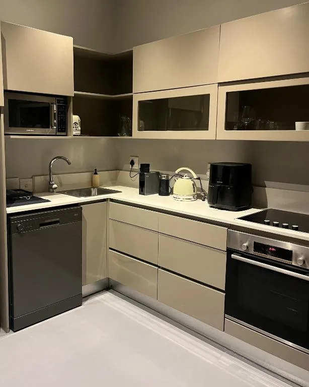Modern kitchen with cream cabinetry, black appliances, and stainless steel sink