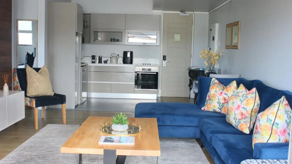 Modern lounge with blue sofa, wooden coffee table, and open-plan kitchen
