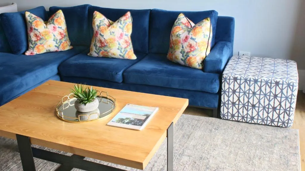 Blue sofa with floral cushions and wooden coffee table in living room