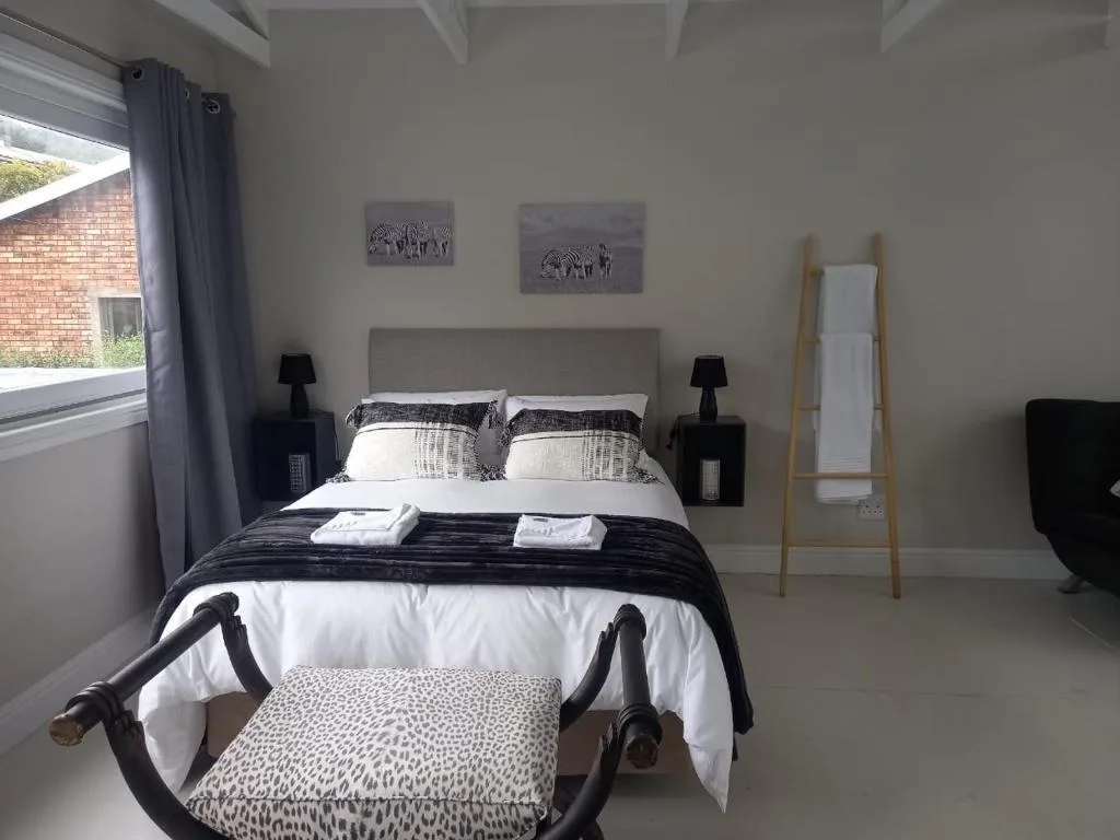 Bright bedroom with double bed, black nightstands, and wildlife wall art