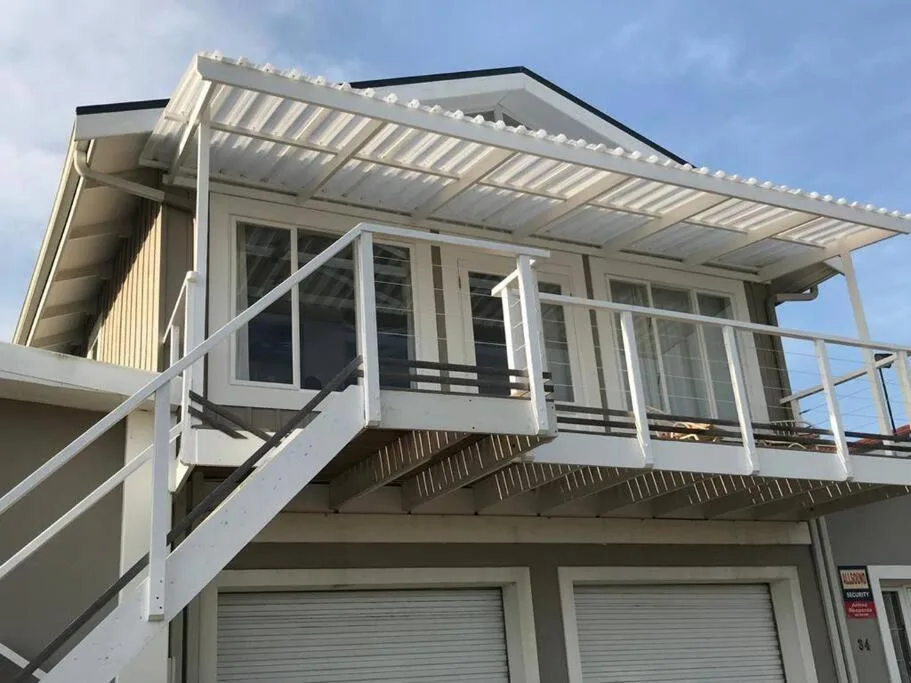 Modern white apartment building with elevated deck and metal railings