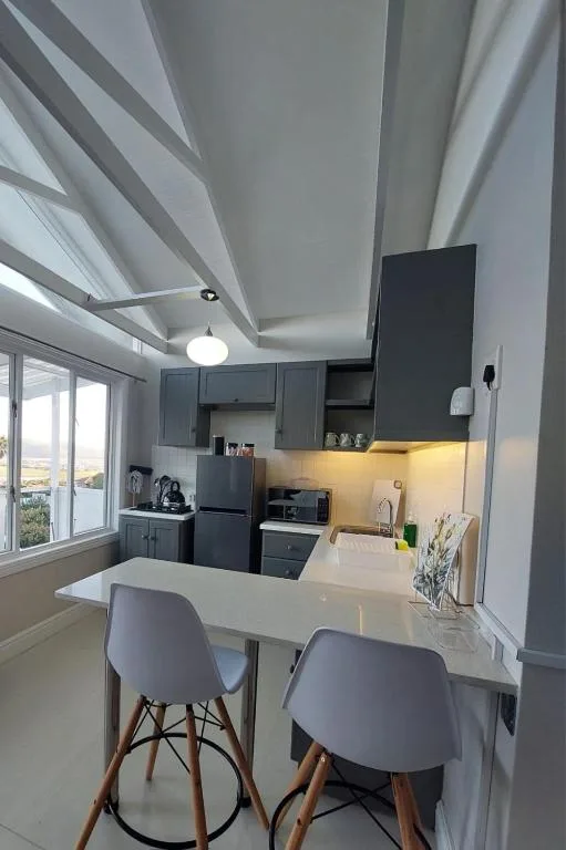 Modern kitchen with dark cabinetry, white countertops, and bar seating for two