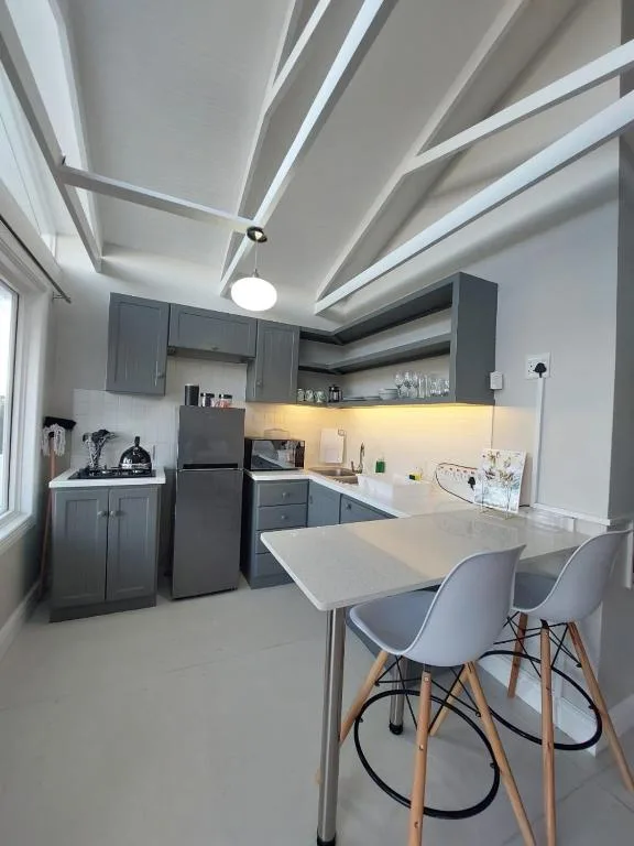 Modern kitchen with dark cabinetry, white countertops, and dining chairs