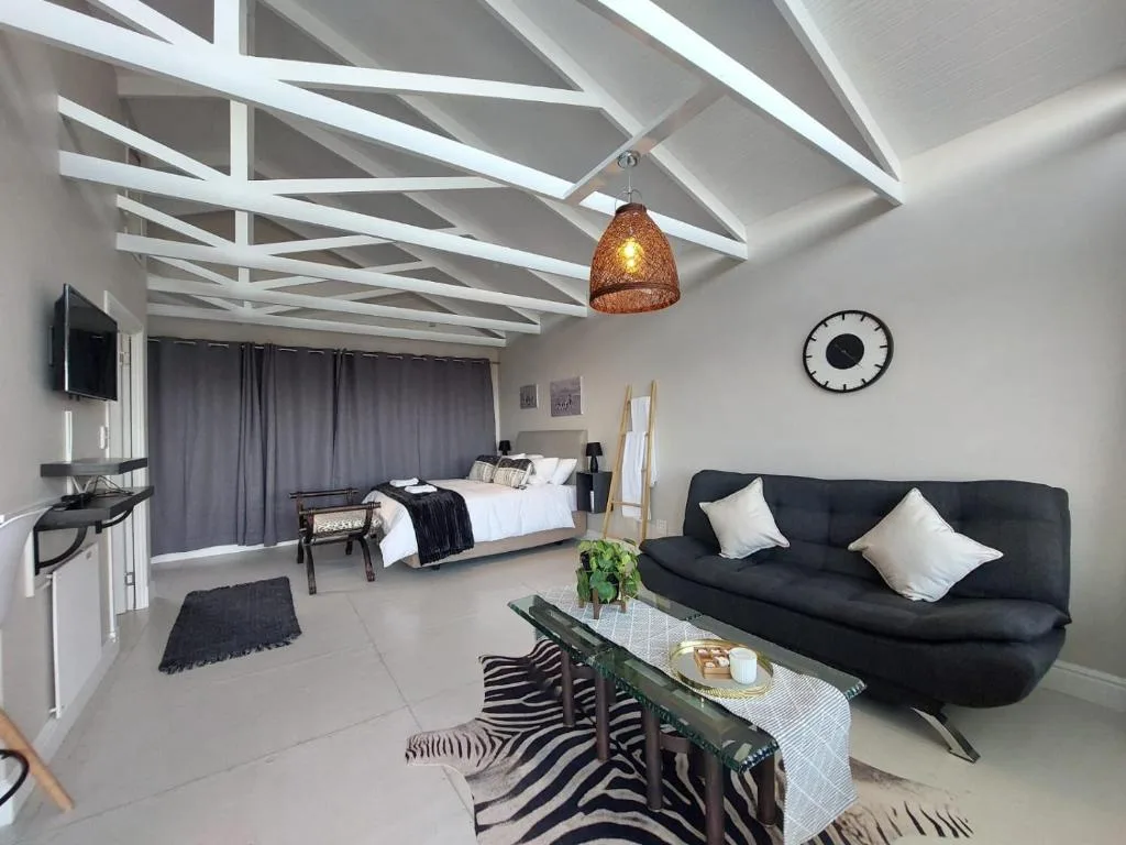 Modern lounge with black sofa, white pillows, and exposed beam ceiling