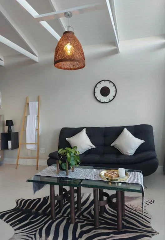 Modern lounge with black sofa, white cushions, and woven pendant light