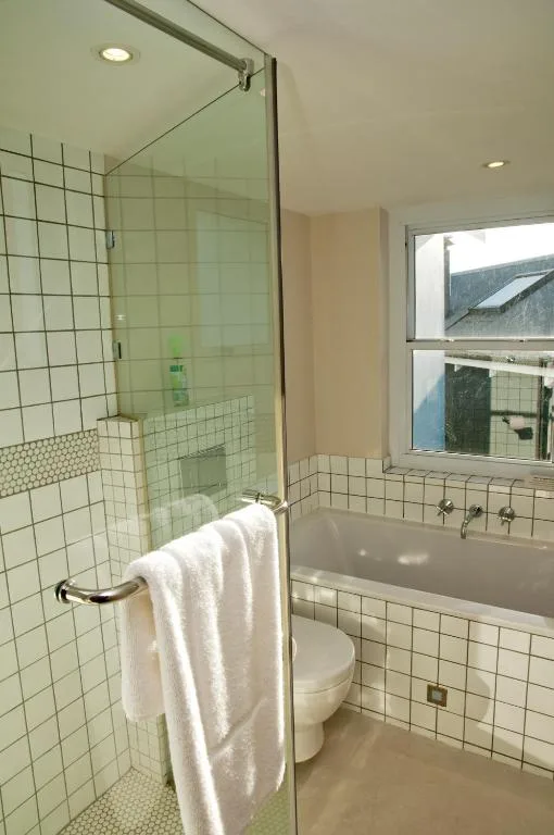 Modern bathroom with glass shower enclosure, white tile, and bathtub
