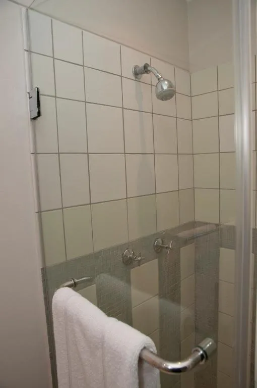 Shower enclosure with tiled walls, chrome fixtures, and white towel rail