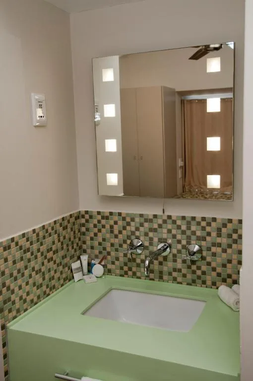 Modern bathroom with lit mirror, green vanity, and mosaic tile backsplash