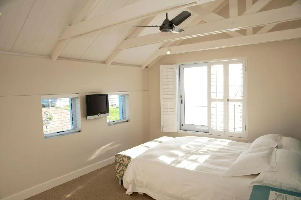 Bright bedroom with queen bed, vaulted ceiling, ceiling fan, and ocean views