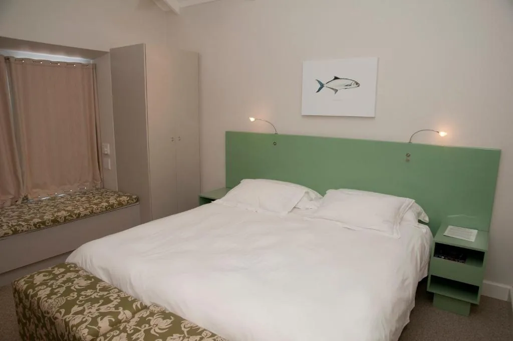 Modern bedroom with queen bed, green headboard, and coastal decor artwork
