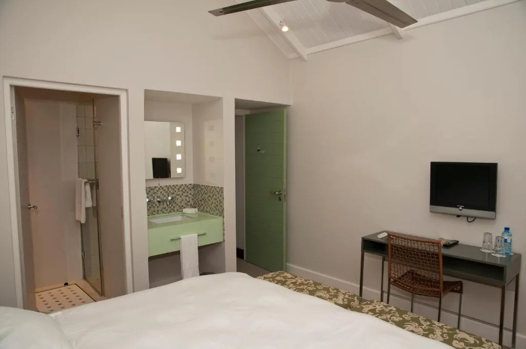 Bedroom with queen bed, TV, desk, and ensuite bathroom with green door