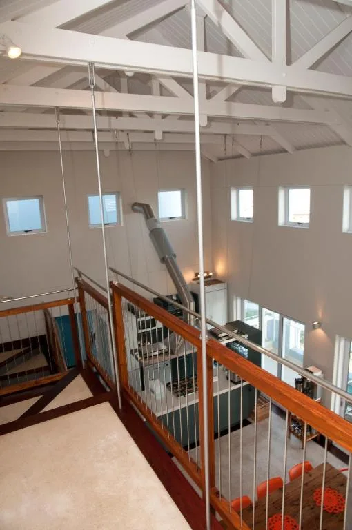 Modern mezzanine loft with wooden railings and cathedral ceiling