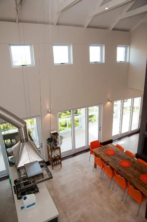 Bright dining area with wooden table and orange chairs, high ceilings