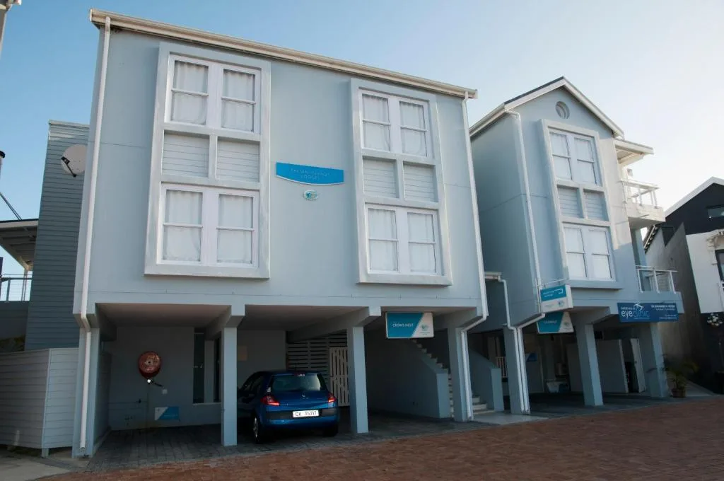Modern blue and white multi-story apartment building with large windows and carport