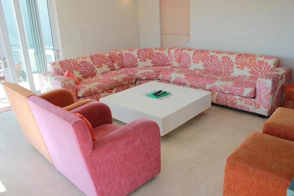 Spacious living room with pink tropical patterned sectional and colorful accent chairs