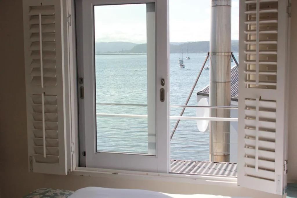 Scenic lagoon view with moored sailboats and mountains through open doors