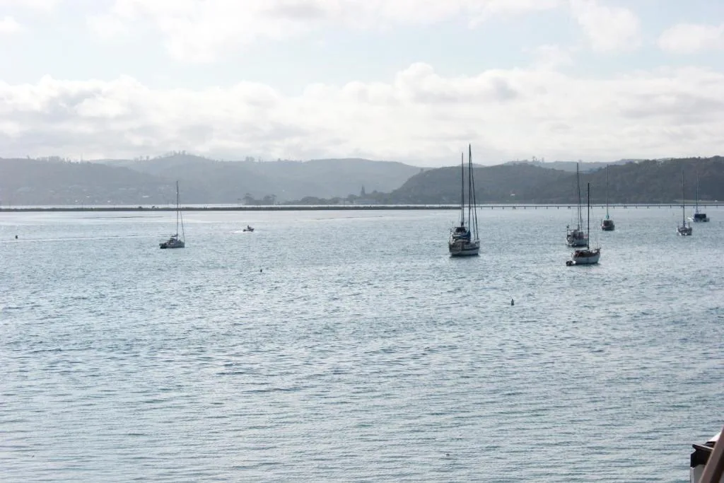 Scenic lagoon view with moored sailboats and distant mountains