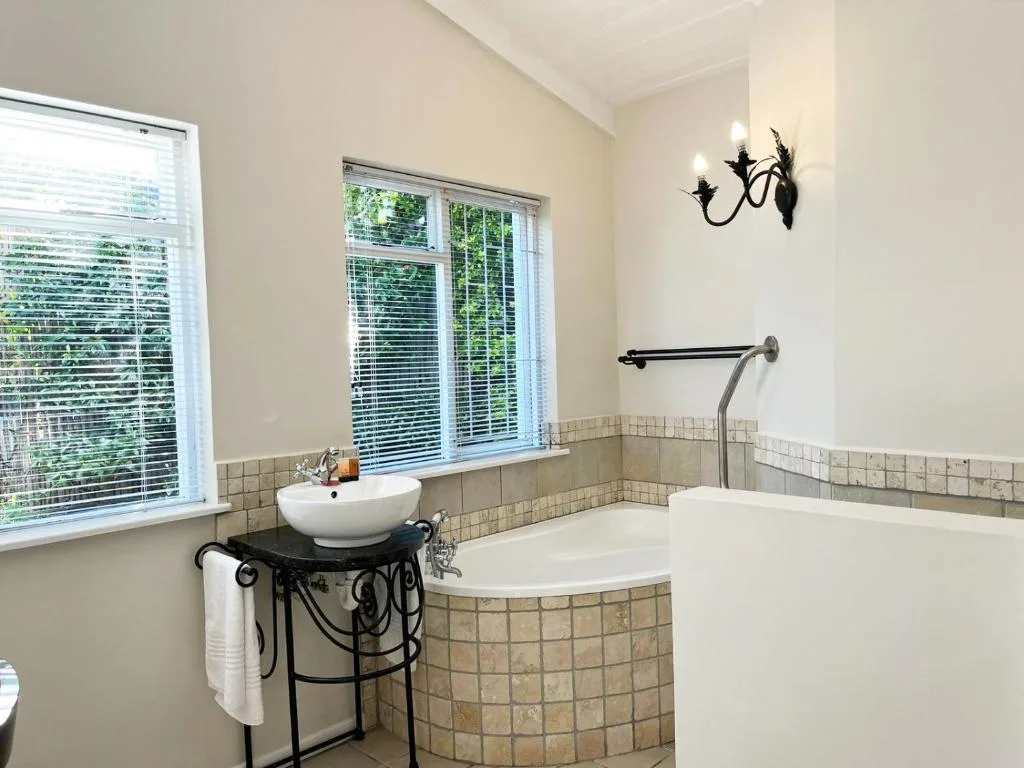 Bright bathroom with vessel sink, soaking tub, and garden views through windows