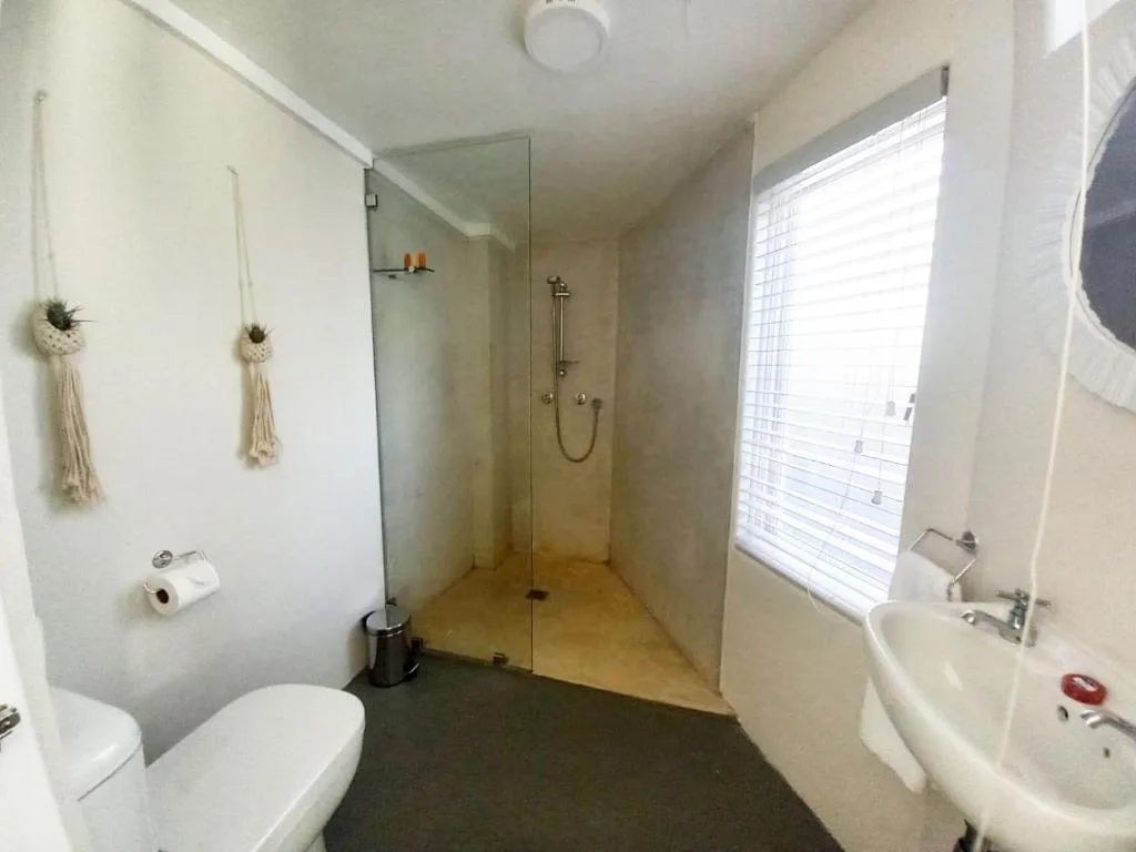 Modern bathroom with walk-in shower, toilet, sink, and natural window light