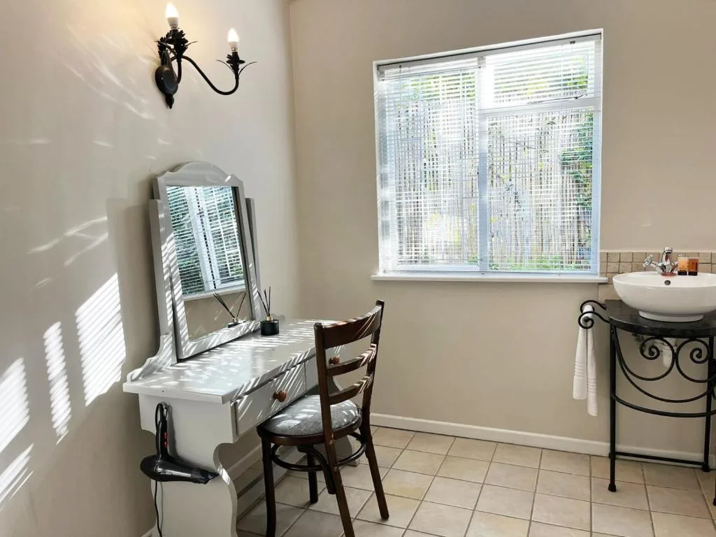 Bright bathroom with vanity, mirror, sink, and decorative black wall sconce