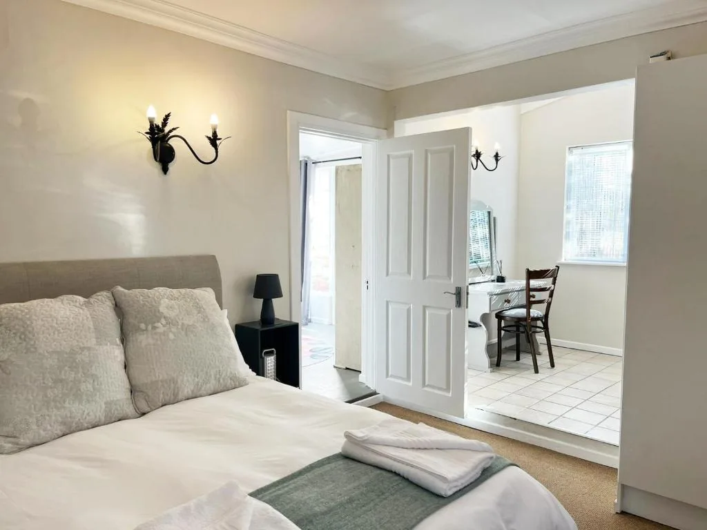Bright bedroom with double bed, elegant wall sconces, and ensuite bathroom access
