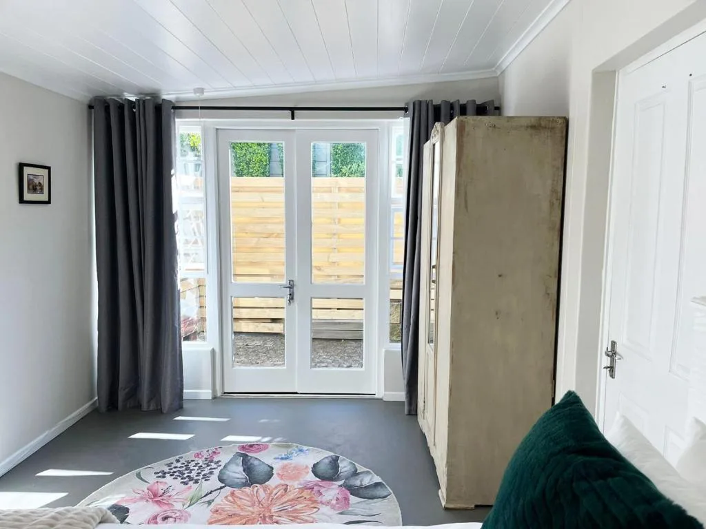 Bright studio bedroom with glass doors opening onto wooden deck