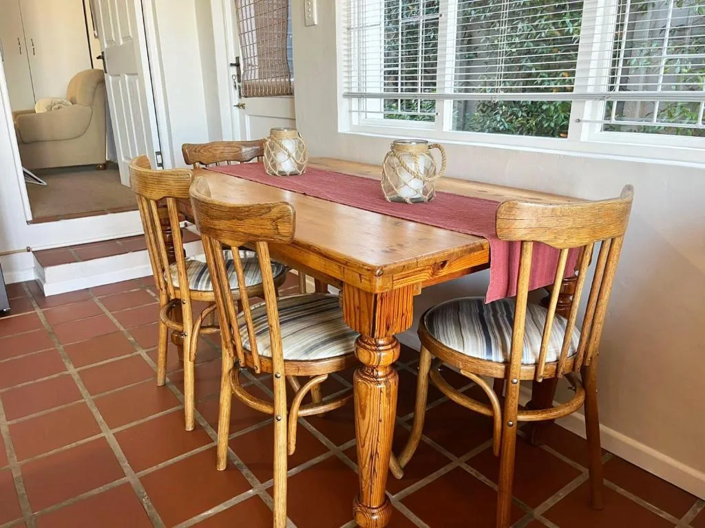 Wooden dining table with four chairs and terracotta tile flooring