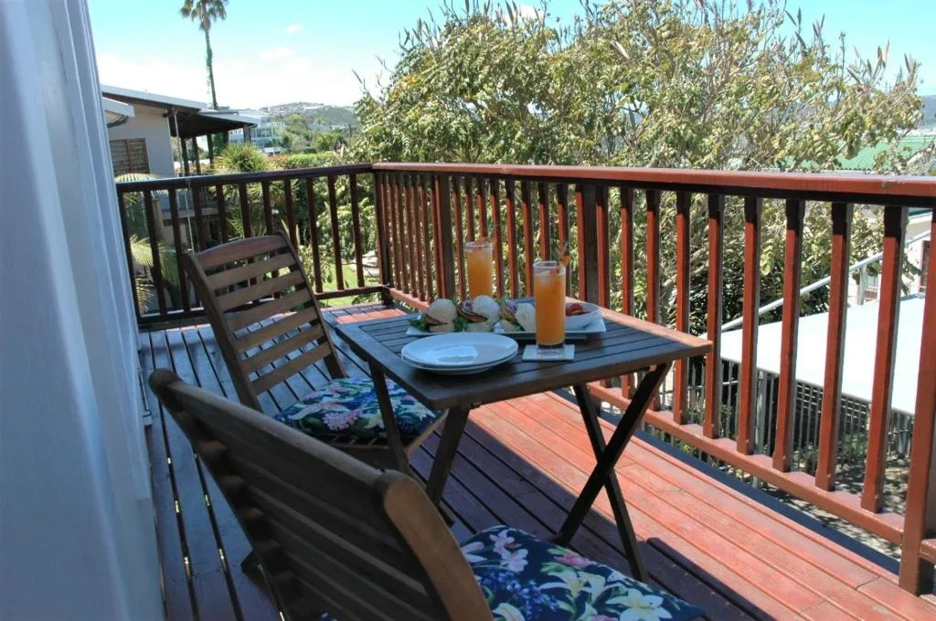 Wooden deck with dining table, chairs, and hillside views over Knysna