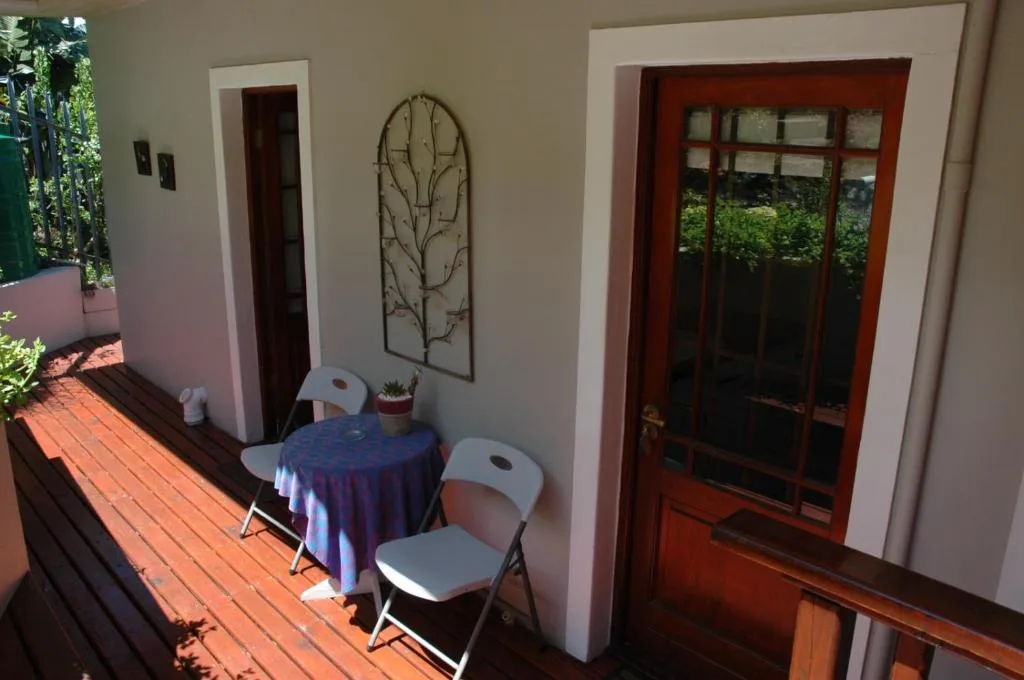 Shaded deck area with small table, folding chairs, and garden views