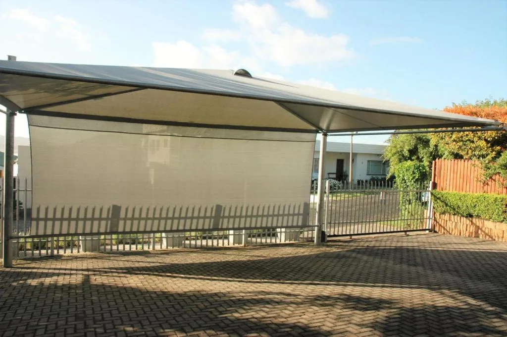 Covered patio with retractable awning and brick paving overlooking garden