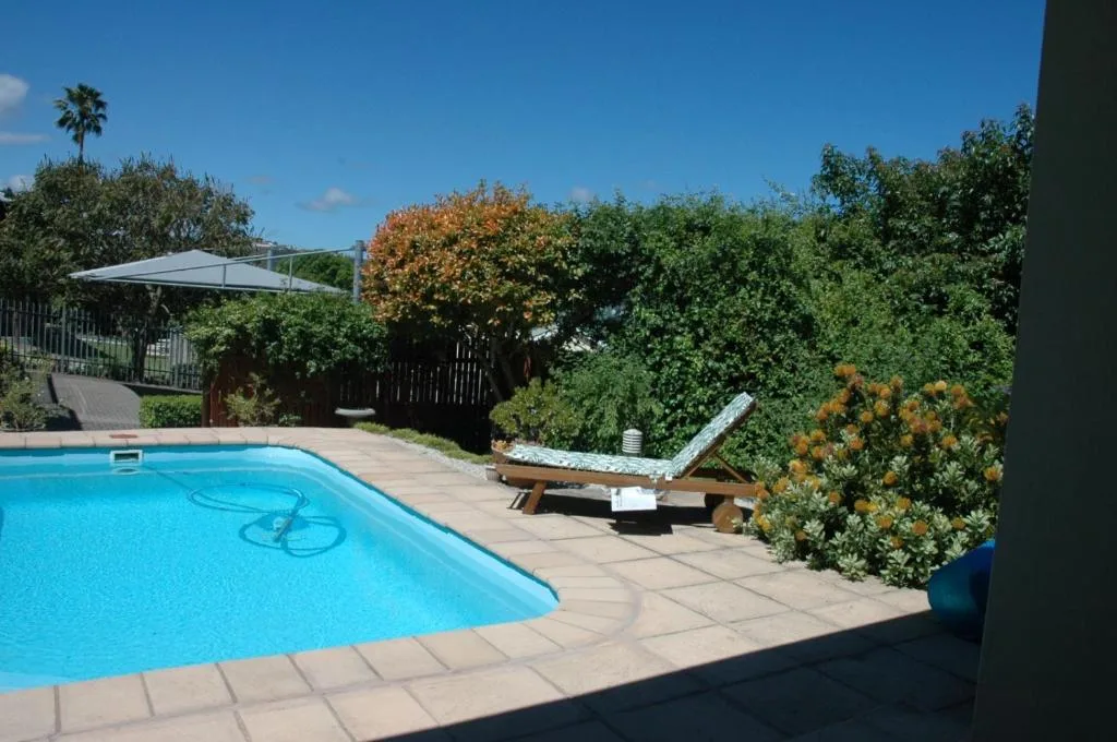 Swimming pool with lounger surrounded by lush garden landscaping
