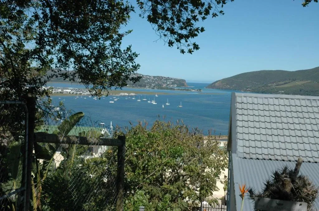 Scenic coastal bay view with sailboats, forested hillsides, and clear blue water