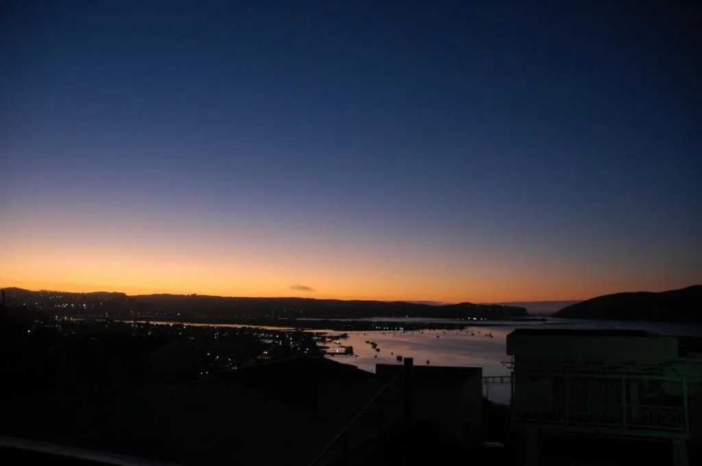 Sunset over Knysna Lagoon with mountains and waterfront lights