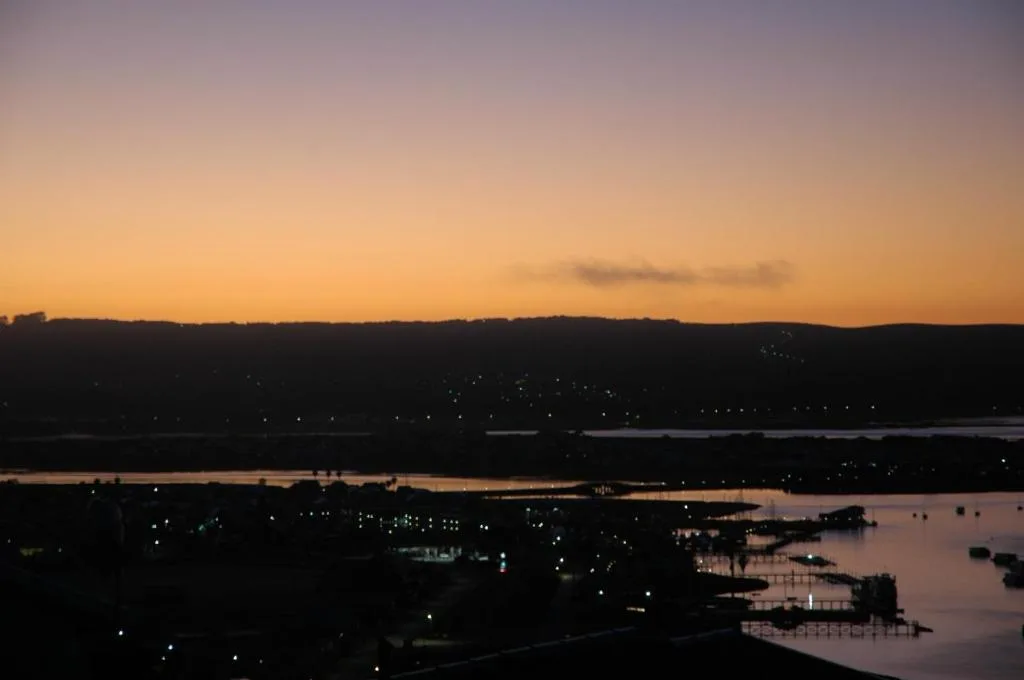 Sunset over Knysna lagoon with forested hills and twinkling town lights