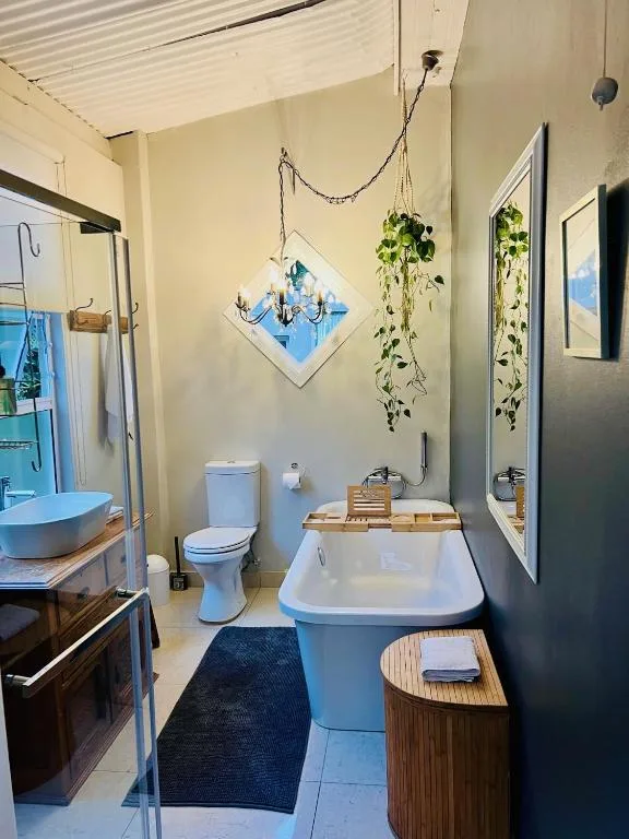 Modern bathroom with freestanding tub, toilet, and decorative hanging plants
