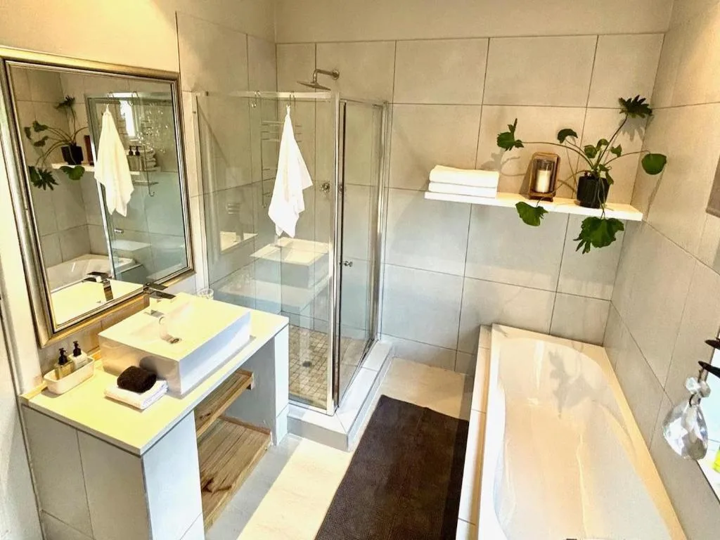 Modern bathroom with vanity, shower enclosure, bathtub, and decorative plants