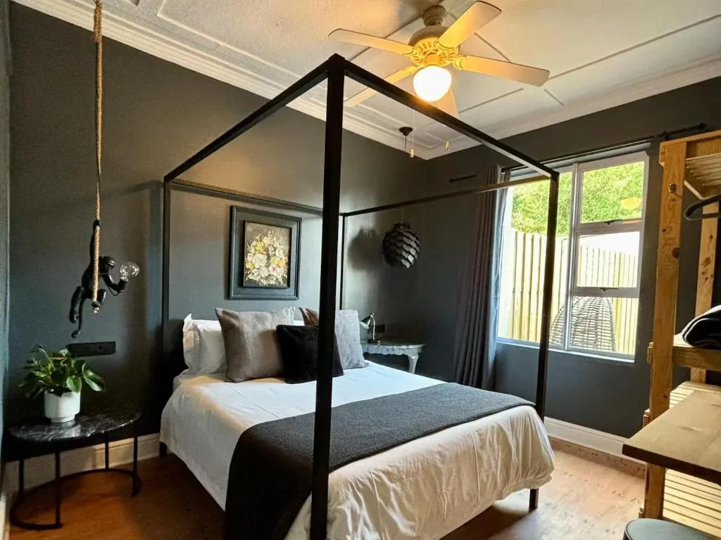Modern bedroom with black four-poster bed and stylish dark accent wall decor