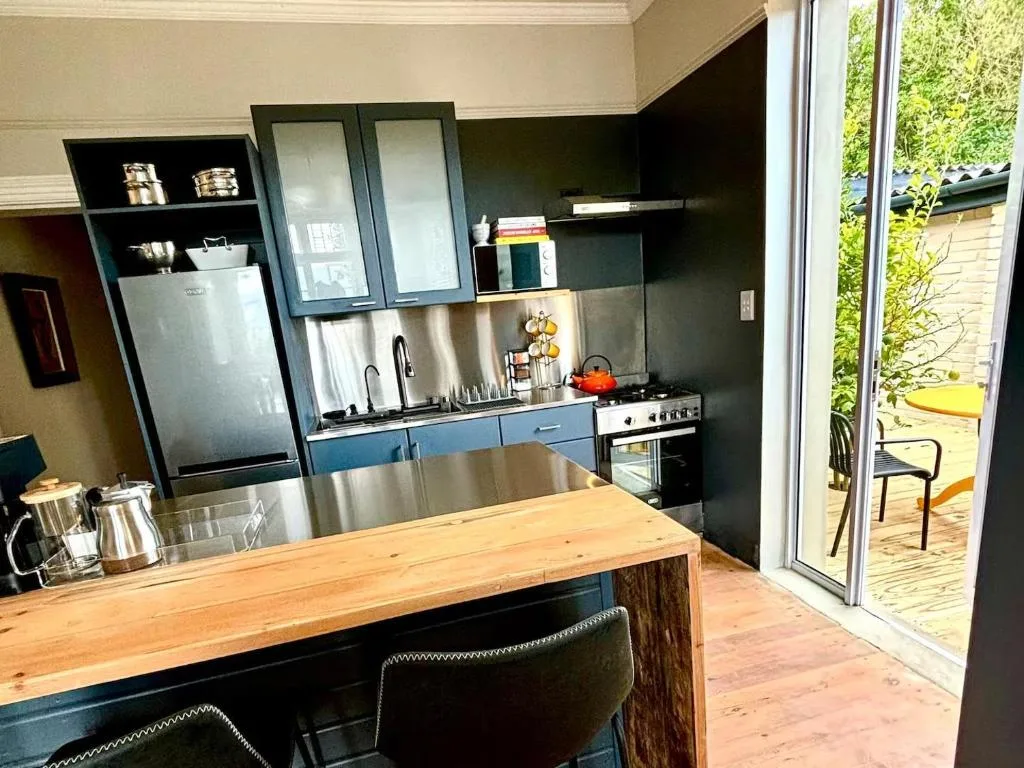 Modern kitchen with stainless steel appliances, wooden island counter, and garden views