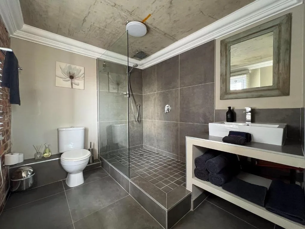 Modern bathroom with walk-in shower, vanity sink, and toilet fixtures