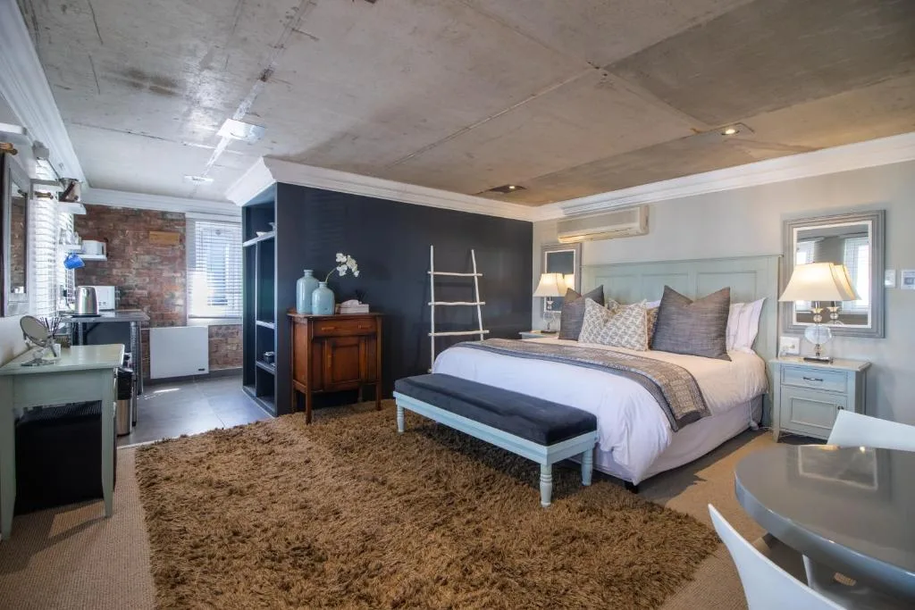 Spacious bedroom with queen bed, dark accent wall, and modern furnishings