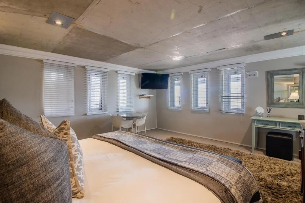 Modern bedroom with queen bed, multiple windows, TV, and en-suite bathroom