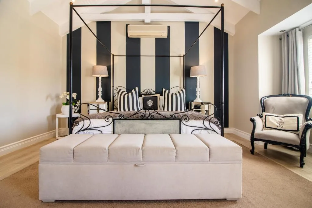 Elegant bedroom with black four-poster bed and striped cushions