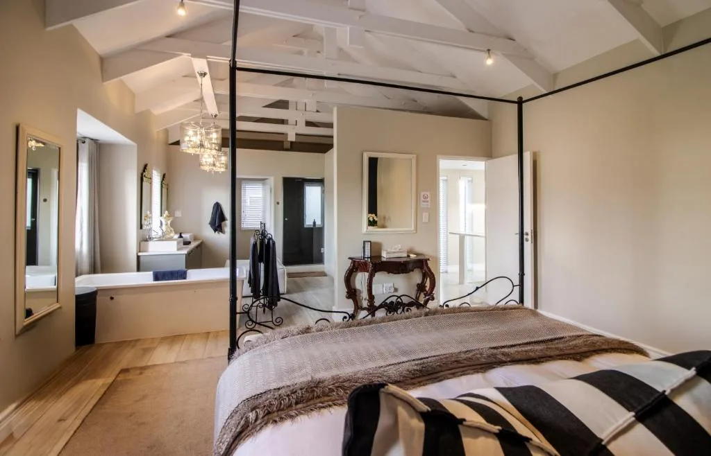 Spacious bedroom with four-poster bed and ensuite bathroom visible