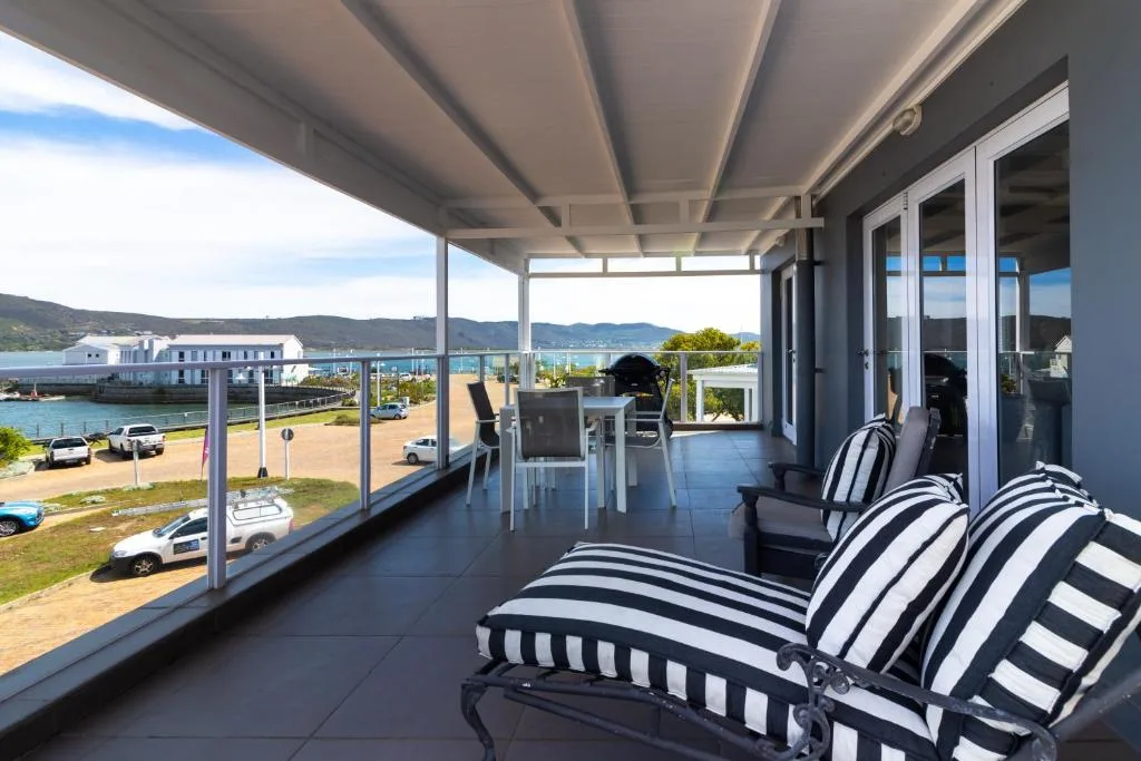 Covered waterfront deck with striped loungers overlooking Knysna Lagoon